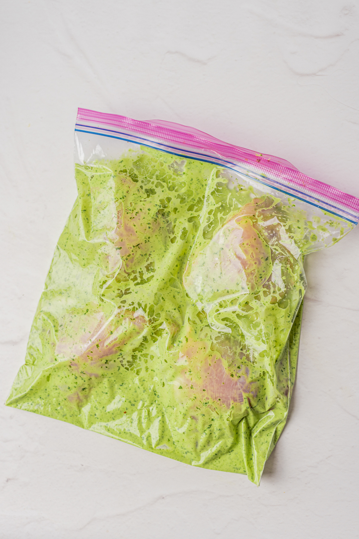raw chicken thighs with dressing in a ziploc bag to marinate