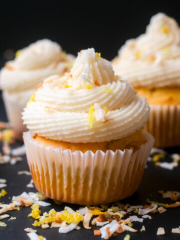 lemon coconut cupcake frosted and topped with toasted coconut and lemon zest